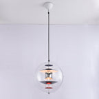 The same chrome-and-red Clérachic sphere pendant, now switched on, with a warm glow lighting the discs inside the acrylic sphere.