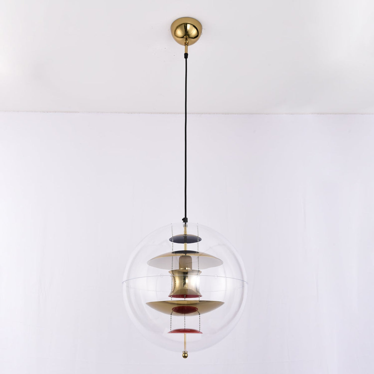 Seen close to the gold canopy, this Clérachic sphere pendant glows with brass-toned discs, a white upper disc and red dishes.