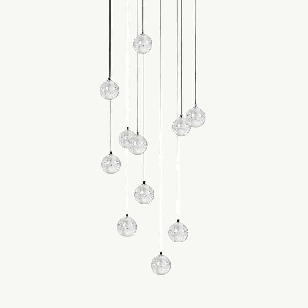 A Clérachic pendant light on a plain white backdrop, a loose cluster of clear glass spheres hung at different heights on thin cords.