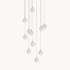A Clérachic pendant light on a plain white backdrop, a loose cluster of clear glass spheres hung at different heights on thin cords.