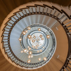Looking up a spiral staircase, this Clérachic pendant light scatters warm glass spheres down the open well at several heights.