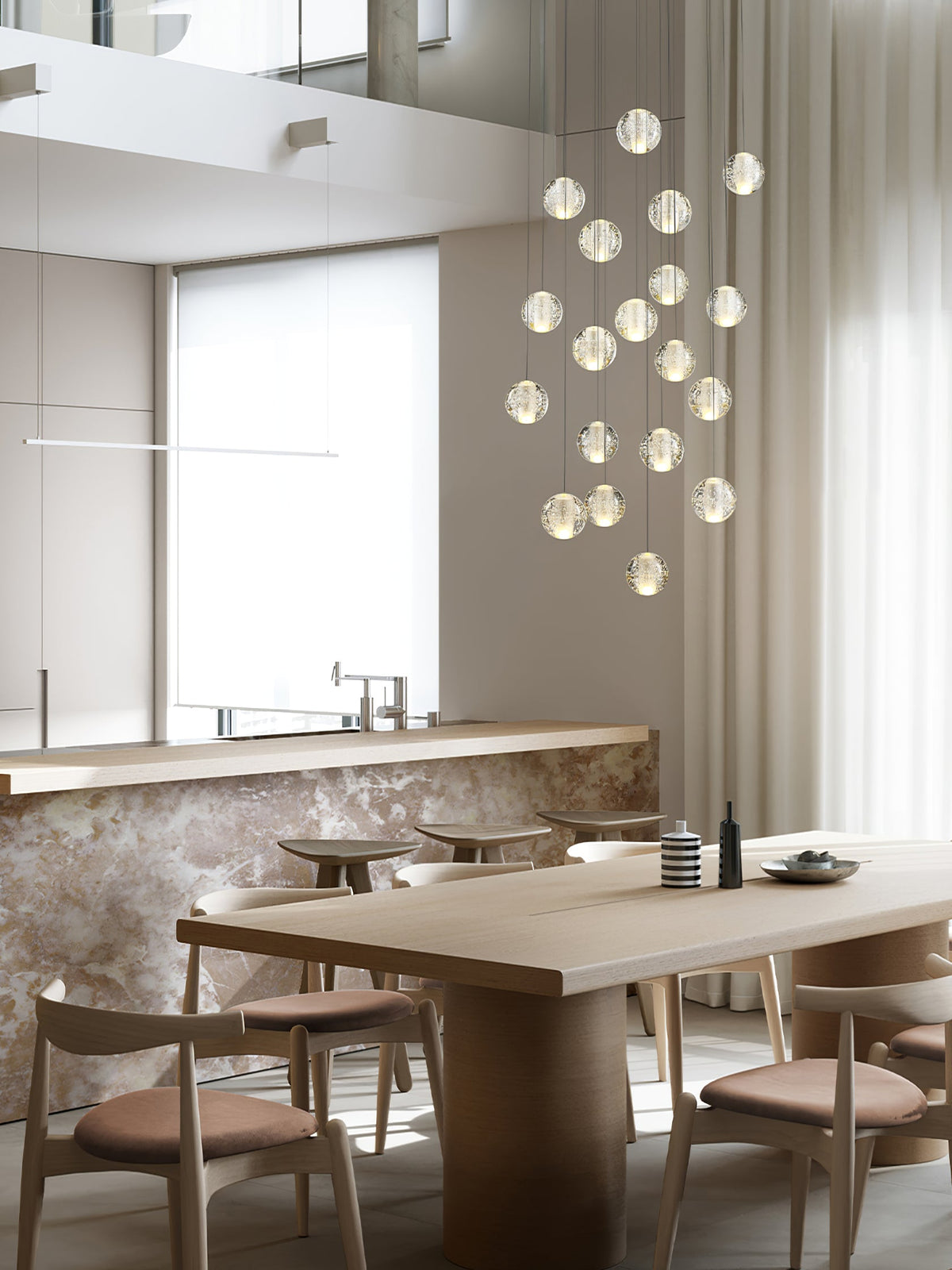 This Clérachic pendant light hangs as a loose group of frosted spheres above a wooden dining table and a stone-fronted counter.