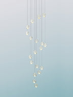 A column of pale glass spheres from this Clérachic pendant light against a soft blue-green gradient, hung on fine cords.