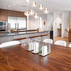 Above a walnut dining table and kitchen island, this Clérachic pendant light hangs a small group of glowing glass spheres.