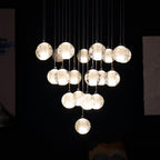 Against a black background, this Clérachic pendant light shows about twenty warmly lit spheres hung in a dense, rounded cluster.