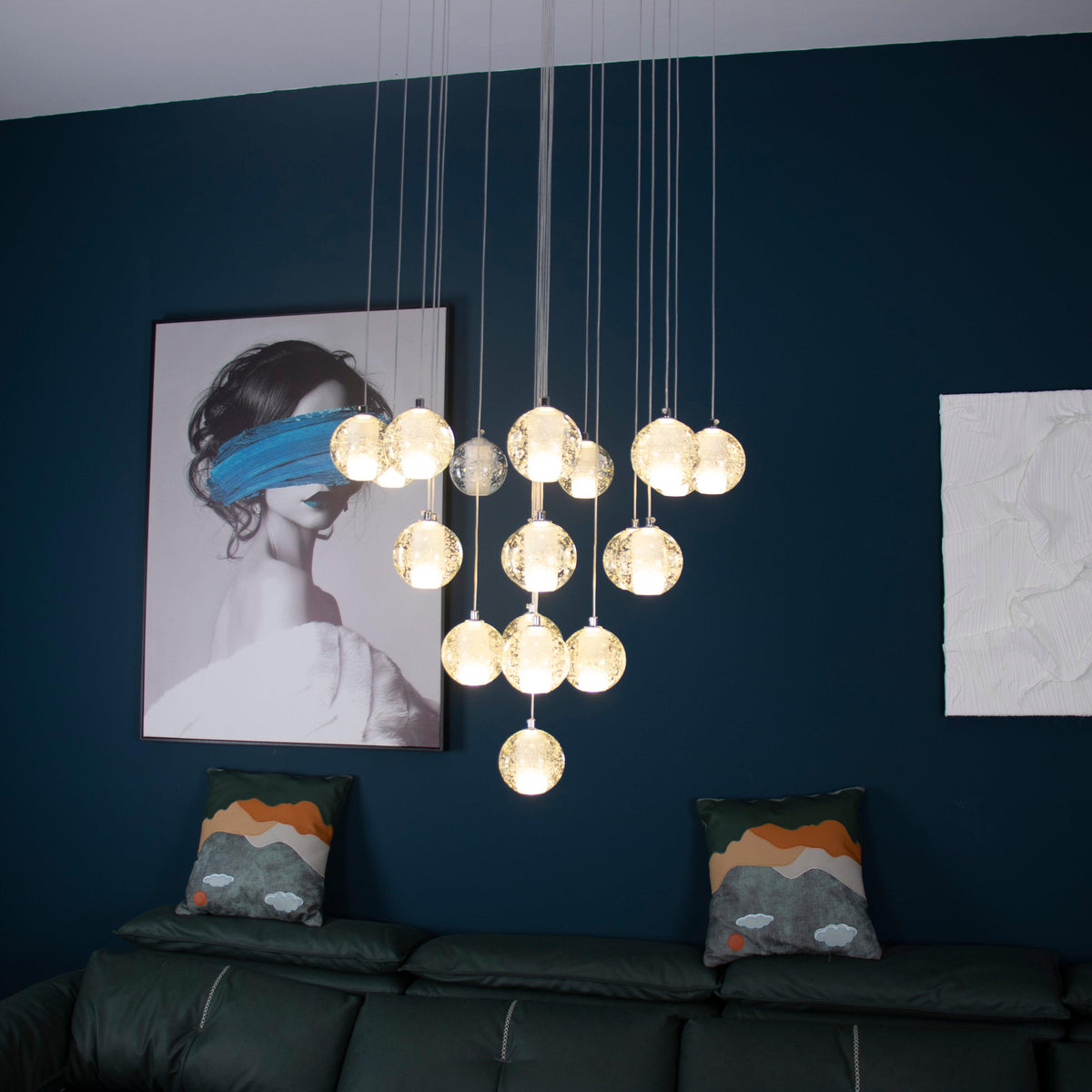 In a living room with a deep blue wall and green leather sofa, this Clérachic pendant light hangs a lit cluster of spheres.