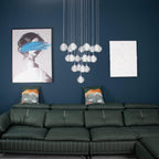 Unlit, the spheres of this Clérachic pendant light hang above a green leather sofa and a framed portrait on a blue wall.