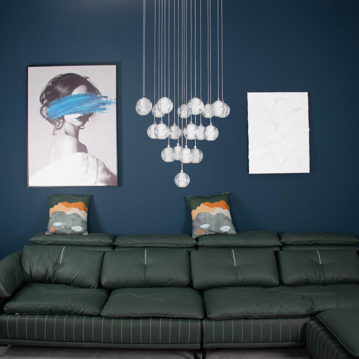Unlit, the spheres of this Clérachic pendant light hang above a green leather sofa and a framed portrait on a blue wall.