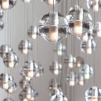 Close view of two clear glass spheres on this Clérachic pendant light, each with a frosted inner core and a warm glow.