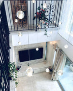 Seen from a gallery above, this Clérachic pendant light hangs a few spheres down into a living room with a wall-mounted screen.