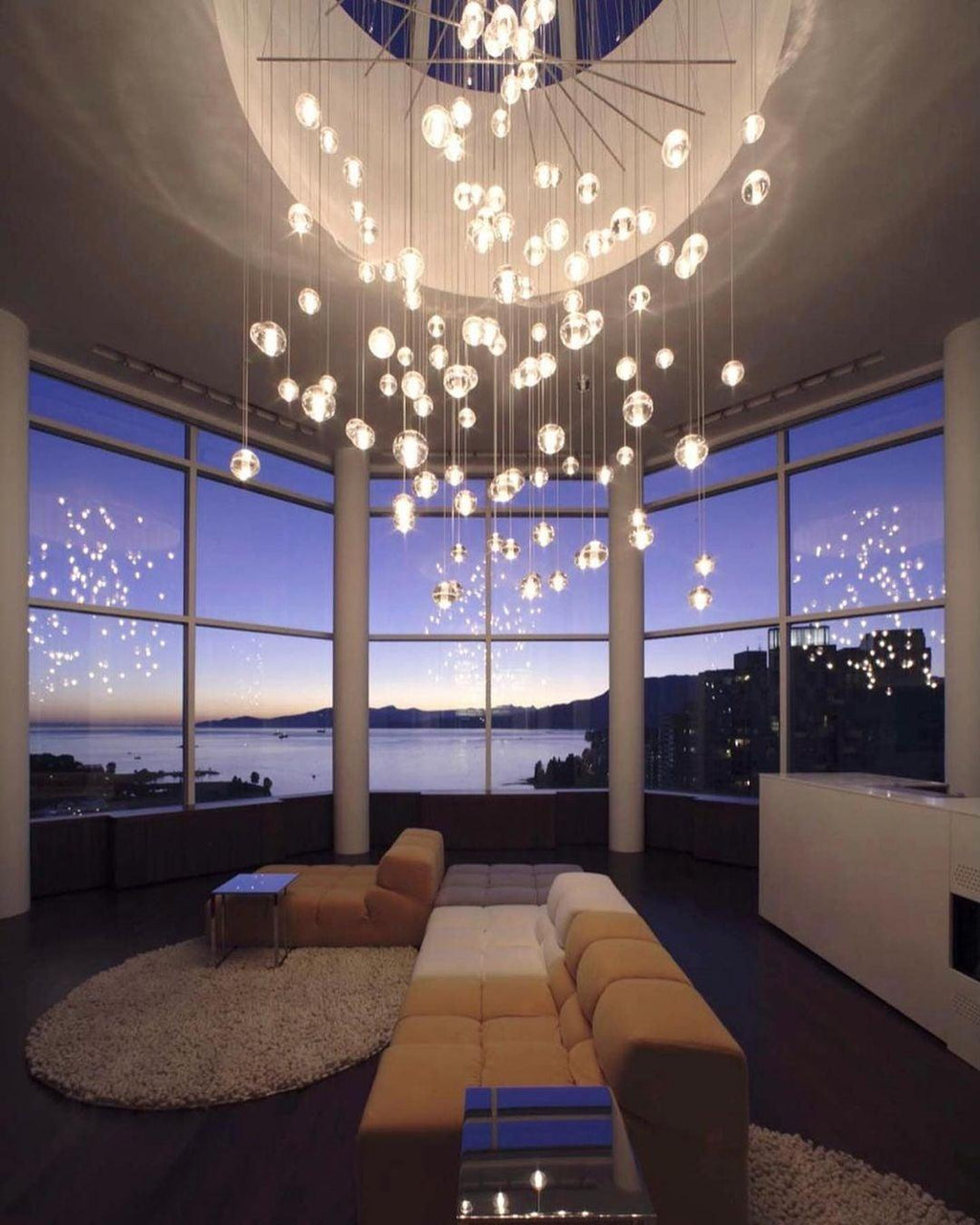 A large burst of lit spheres from this Clérachic pendant light radiates from a round ceiling recess in a sunset-lit corner room.