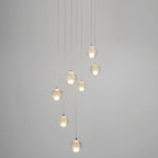 Eight spheres from this Clérachic pendant light hang on long cords at different heights against a plain grey wall.