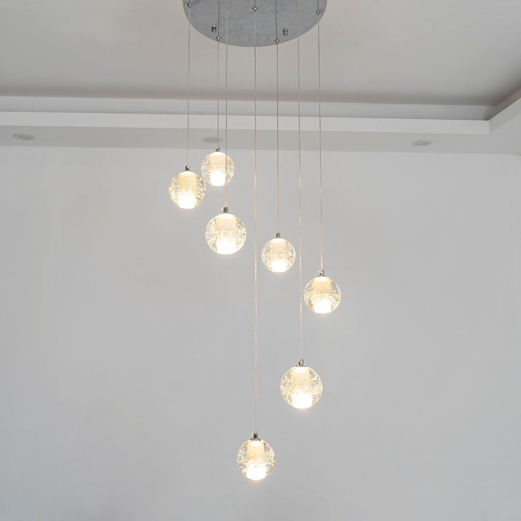 This Clérachic pendant light hangs nine spheres from a round chrome ceiling plate, with a recessed ceiling edge behind.