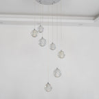 Unlit, the spheres of this Clérachic pendant light hang from a round chrome plate against a pale wall, clear and lightly bubbled.