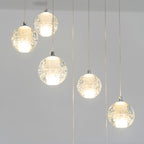 Lit spheres of this Clérachic pendant light hang at staggered heights, each with a warm white core, against a grey wall.