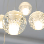 Close view of warm light glowing through the clear, bubble-flecked glass of this Clérachic pendant light, with others softly behind.