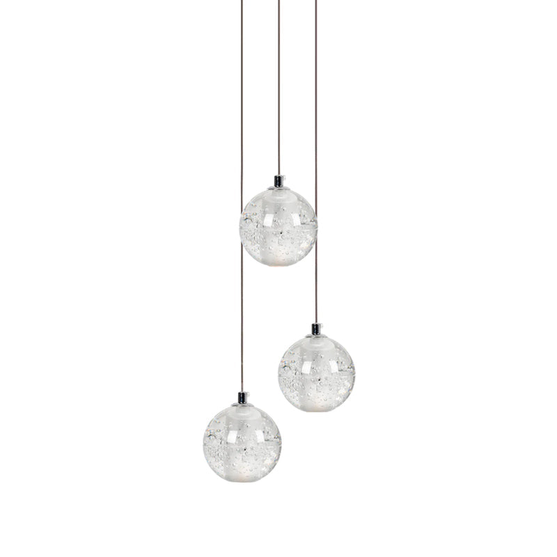 Three clear spheres of this Clérachic pendant light hang at different heights on thin cords against white.
