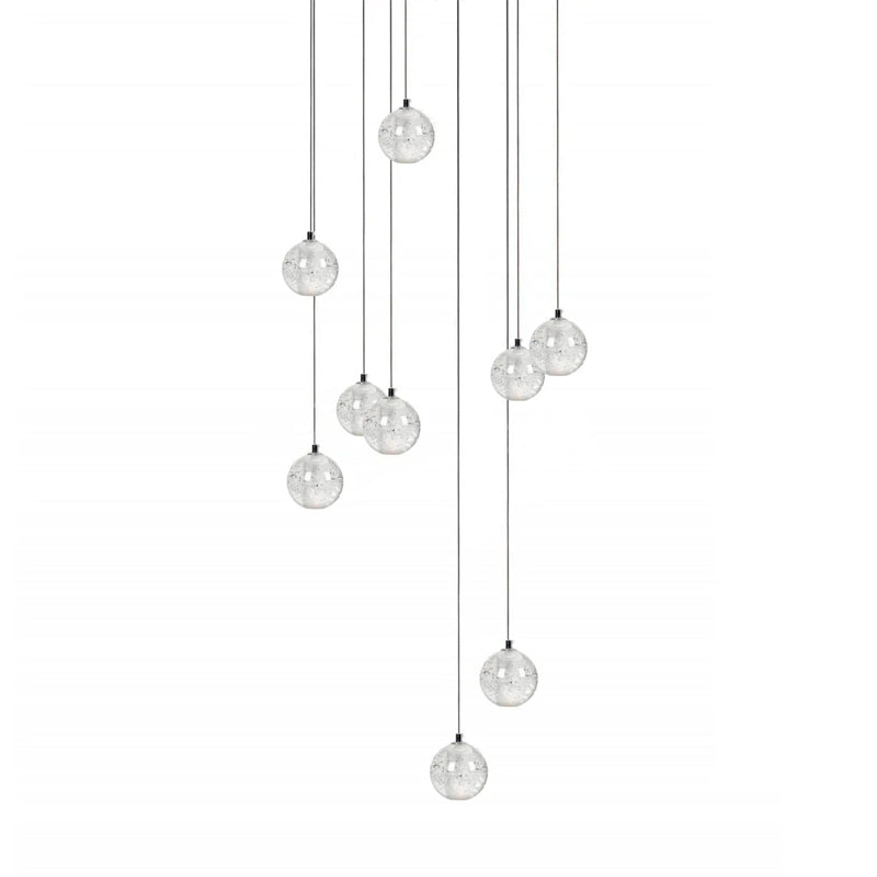 A spread of nine clear spheres from this Clérachic pendant light hangs on dark cords at varied heights on white.