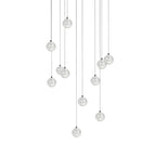 Eleven clear spheres from this Clérachic pendant light hang at uneven heights on thin cords, shown on white.