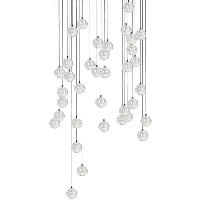 A wide, heavy cluster of clear spheres from this Clérachic pendant light, hung on cords of many lengths on white.