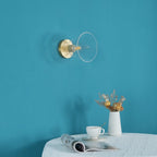 The same light unlit on a teal wall, its clear glass flare and brass plate visible above a small table, a Clérachic flush mount.