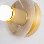 Very close view of the knurled brass socket and round backplate, with a glowing bulb at the left edge, on this Clérachic fitting.