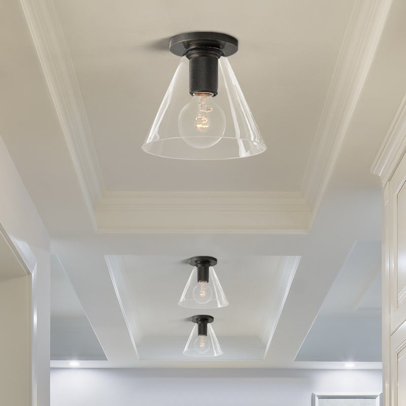Black-fitted flush lights with clear glass shades on a panelled ceiling above a light hallway, a Clérachic flush mount.