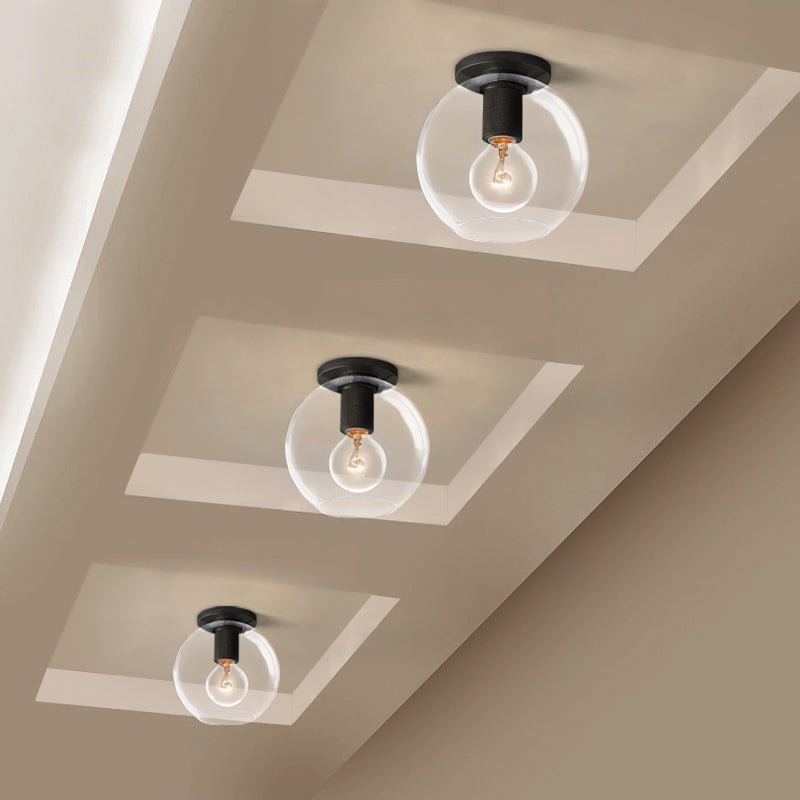 Three globe-shaped glass lights with black fittings in recessed ceiling panels, seen from below, from Clérachic.