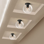 Three globe-shaped glass lights with black fittings in recessed ceiling panels, seen from below, from Clérachic.