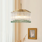 This Clérachic gold and glass chandelier hangs beside sheer curtains, with a gilt-framed painting on the wall behind it.