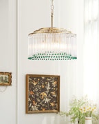 Hanging near a botanical print in a dark wooden frame, this Clérachic glass rod chandelier has a ring of green beads at its base.