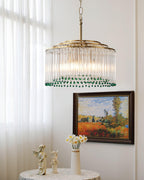 This Clérachic chandelier hangs in front of a framed landscape painting, with small figurines and flowers on a table below.
