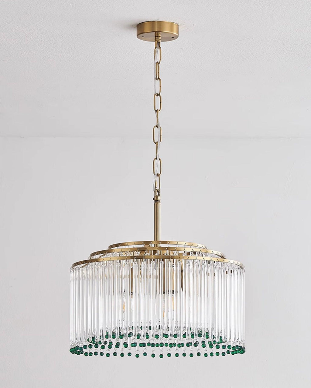 Full-length view of this Clérachic chandelier on its gold chain and ceiling plate, against a pale wall.
