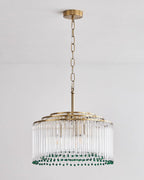 Full-length view of this Clérachic chandelier on its gold chain and ceiling plate, against a pale wall.