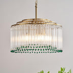 Close view of the clear glass rods and tiered gold rings of this Clérachic chandelier, with green beads at the bottom.