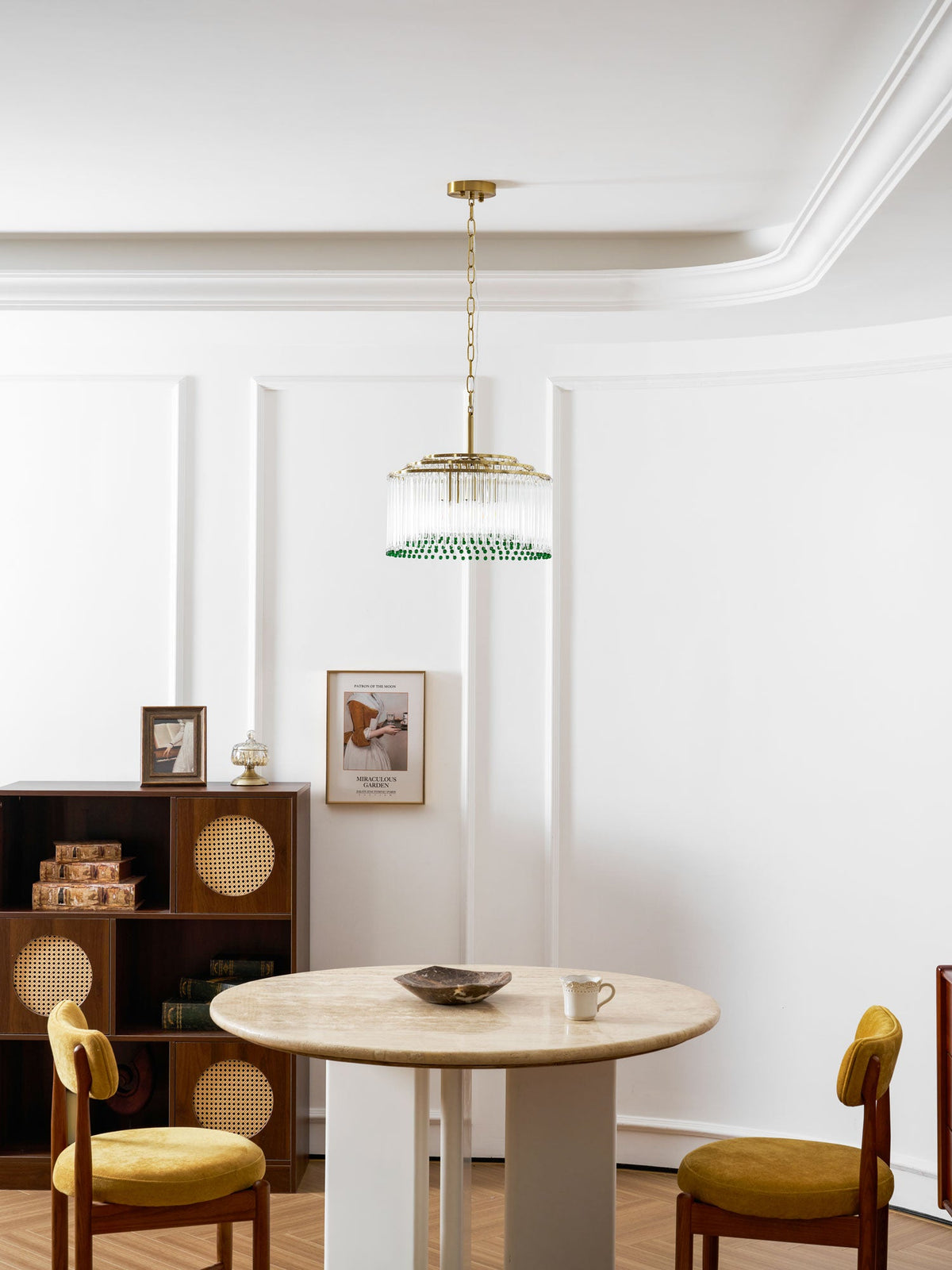 This Clérachic chandelier hangs high above a round dining table with mustard velvet chairs and a rattan-front cabinet.
