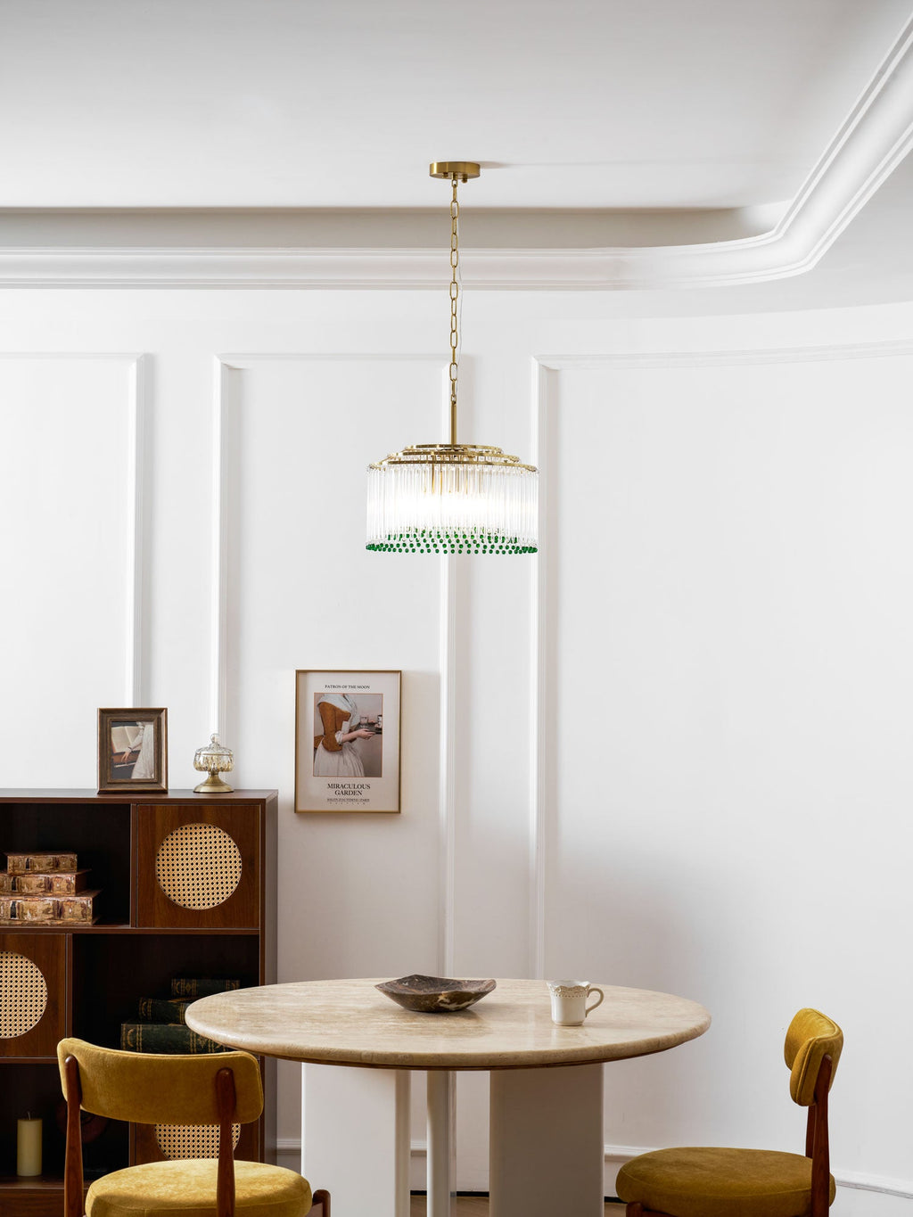This Clérachic chandelier hangs in a white room with cornicing, above a table set with a dish and a cup.