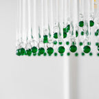 Close view of green glass beads on small rings at the bottom of the clear glass rods on this Clérachic chandelier.