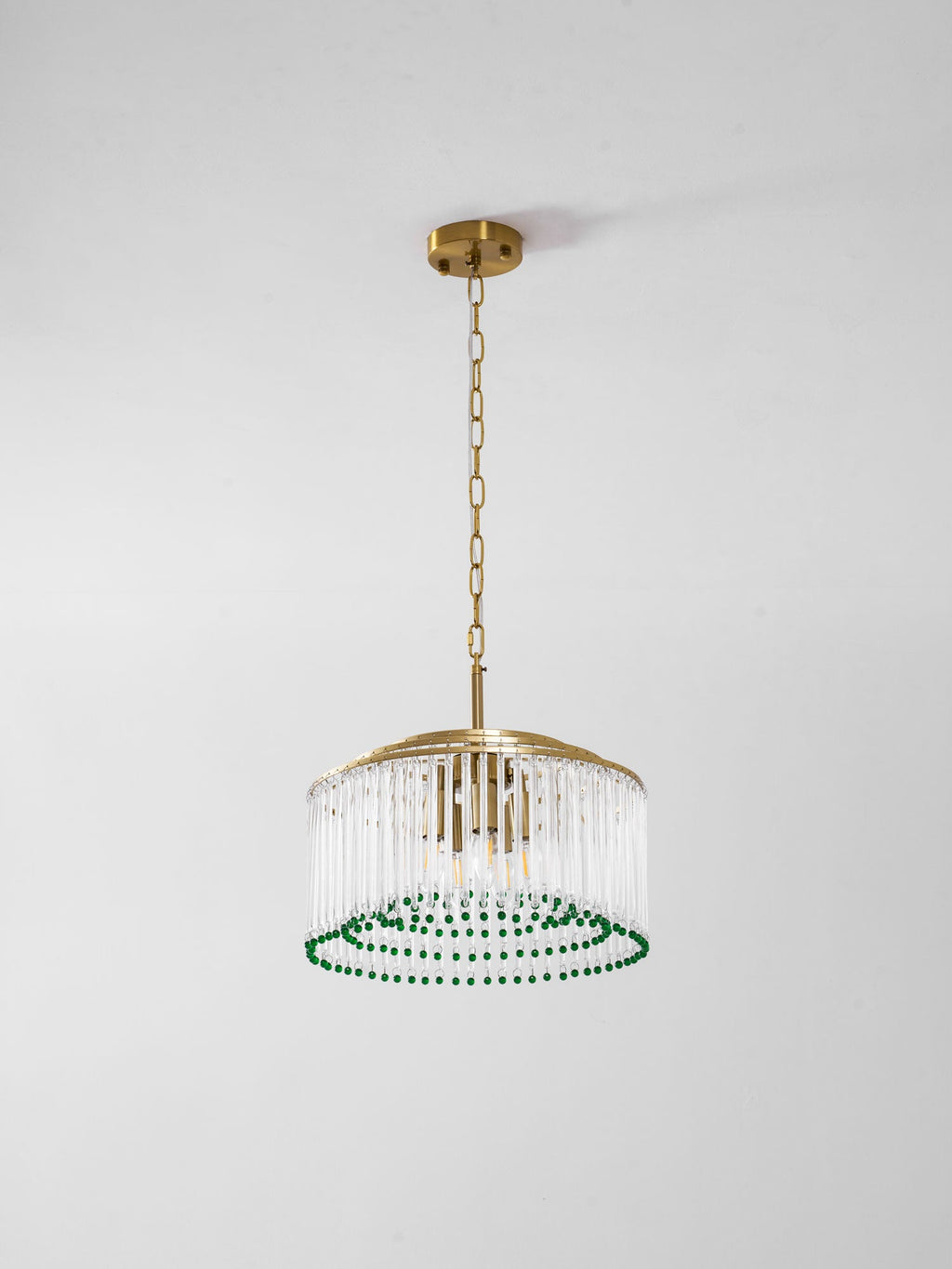 This Clérachic chandelier hangs on a gold chain from a round ceiling plate, shown against a plain grey wall.