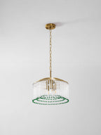 This Clérachic chandelier hangs on a gold chain from a round ceiling plate, shown against a plain grey wall.