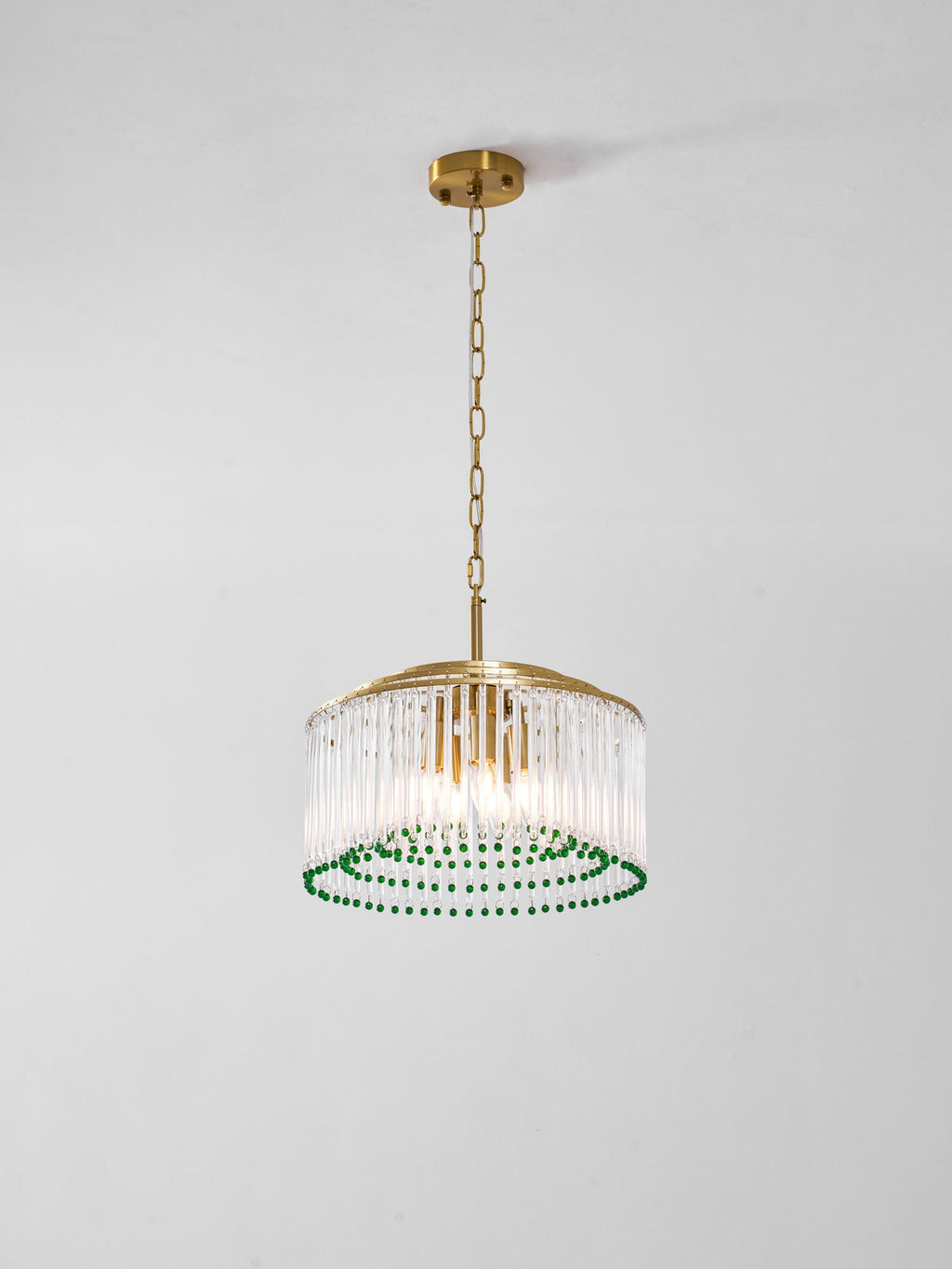 A Clérachic chandelier with candle-style bulbs inside a drum of glass rods, ringed with green beads, on a grey background.
