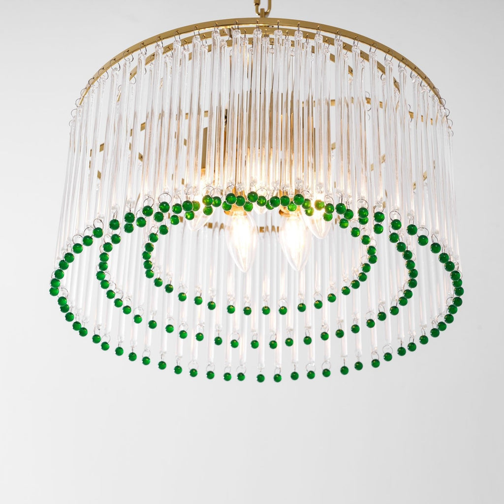 Close view from below of this Clérachic chandelier, with candle bulbs lit inside the glass rods and two rings of green beads.