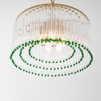 Close view from below of this Clérachic chandelier, with candle bulbs lit inside the glass rods and two rings of green beads.