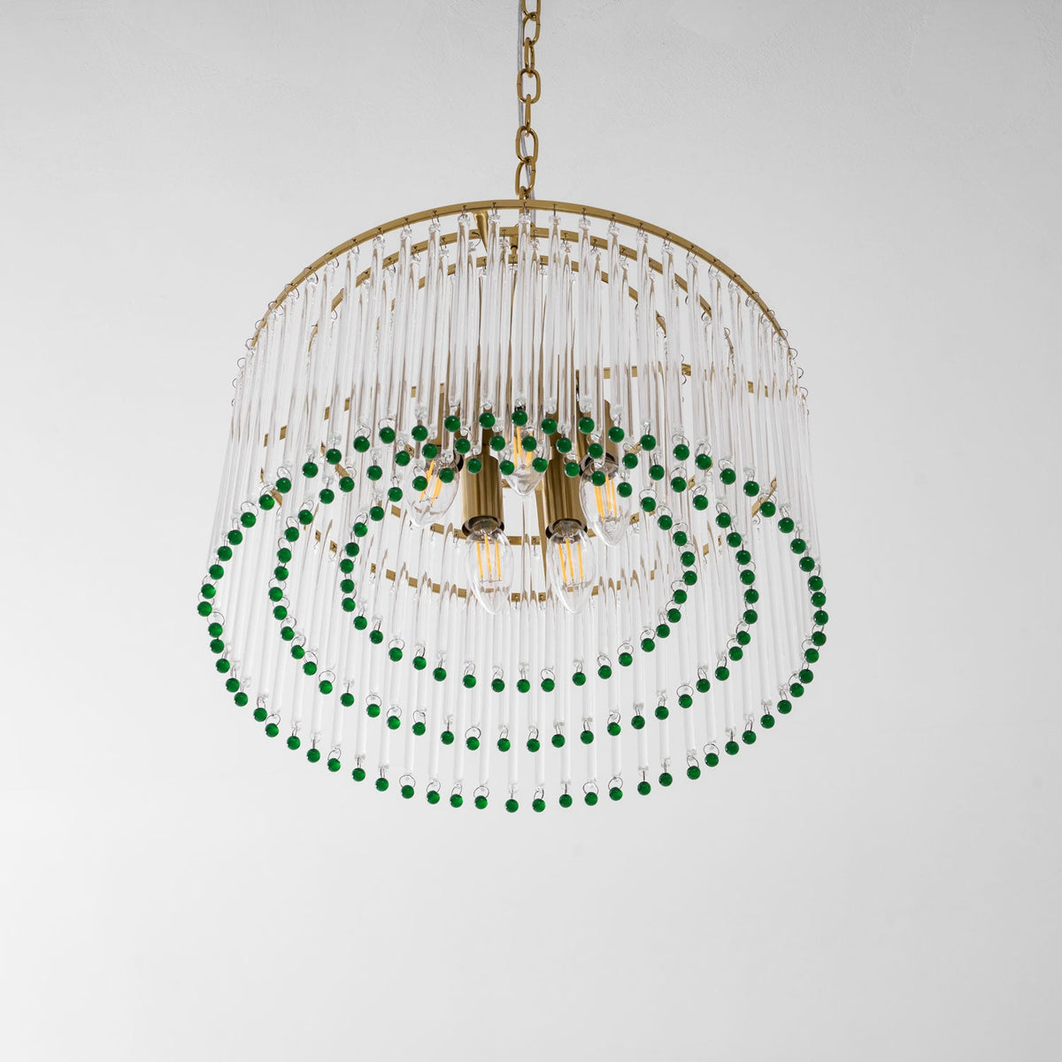 This Clérachic chandelier seen from below shows its brass candle sockets, three rings of green beads and a gold chain above.