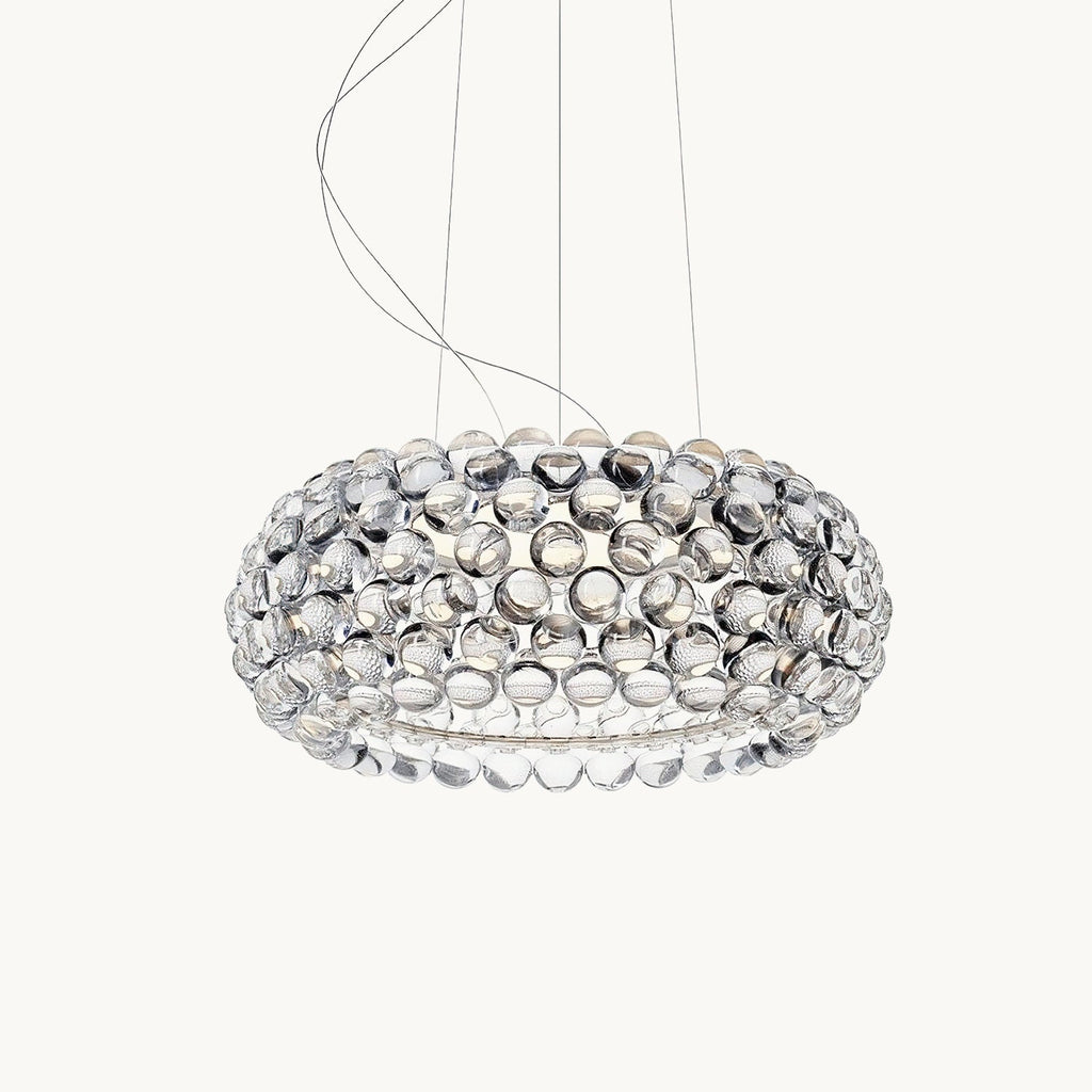 A wide, low pendant covered in clear acrylic spheres hangs from fine cables against a plain white backdrop, shown as this Clérachic pendant.