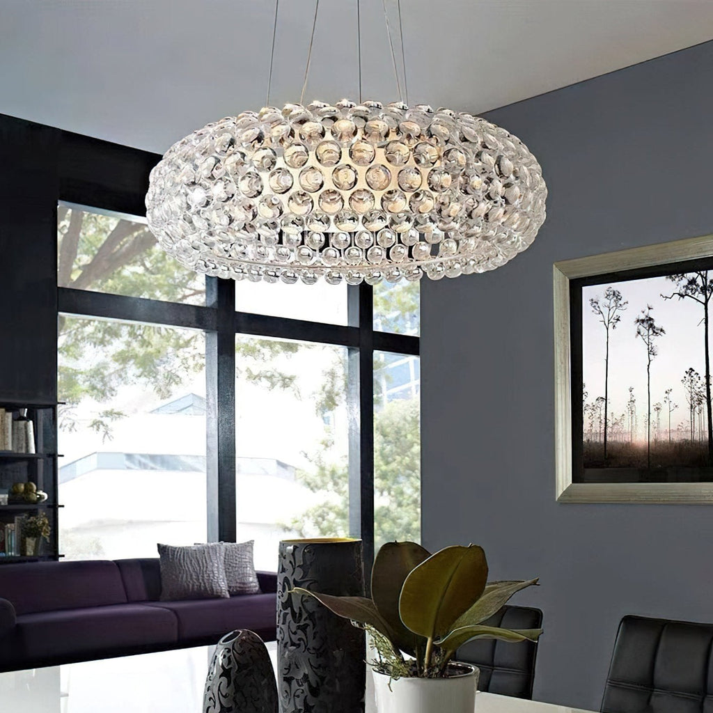 A clear sphere-covered pendant glows above a white table in a grey room with a black-framed window and a purple sofa, from Clérachic.