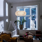 A clear sphere pendant hangs before a tall white-framed window in a child's room with a cot and a bunny lamp, from Clérachic.