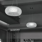 Two clear sphere pendants hang at different heights in a grey-toned room with a concrete ceiling, from Clérachic.