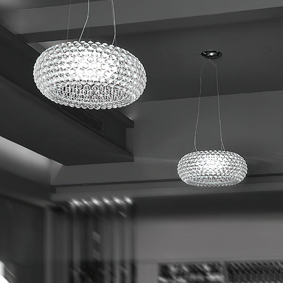 Two clear sphere pendants hang at different heights in a grey-toned room with a concrete ceiling, from Clérachic.
