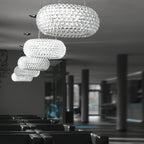 A line of clear sphere pendants of falling sizes hangs through a dark lounge with rows of black seating, from Clérachic.